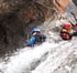 Ein Kletterer in blauer Ausrüstung seilt sich an einem Felsen mit Wasserfall ab.