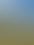 Grüner Traktor mit orangefarbenem Anhänger auf einem Feld unter bewölktem Himmel.
