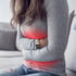 Woman with stomach pain, clutching her abdomen with hands.