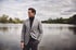 Mann im karierten Sakko steht am See – klassischer Herbstlook mit ruhiger Ausstrahlung.
