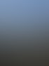 Baustelle mit ausgehobener Grube, Kran und Gebäudefundamenten unter blauem Himmel.