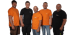 Fünf Männer in orangefarbenen und schwarzen T-Shirts mit STIHL-Logo stehen nebeneinander und lächeln.