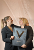 Zwei Frauen halten eine Plakette mit der Aufschrift „Golden Award, Andrea Höhler“ und einem großen „V“.