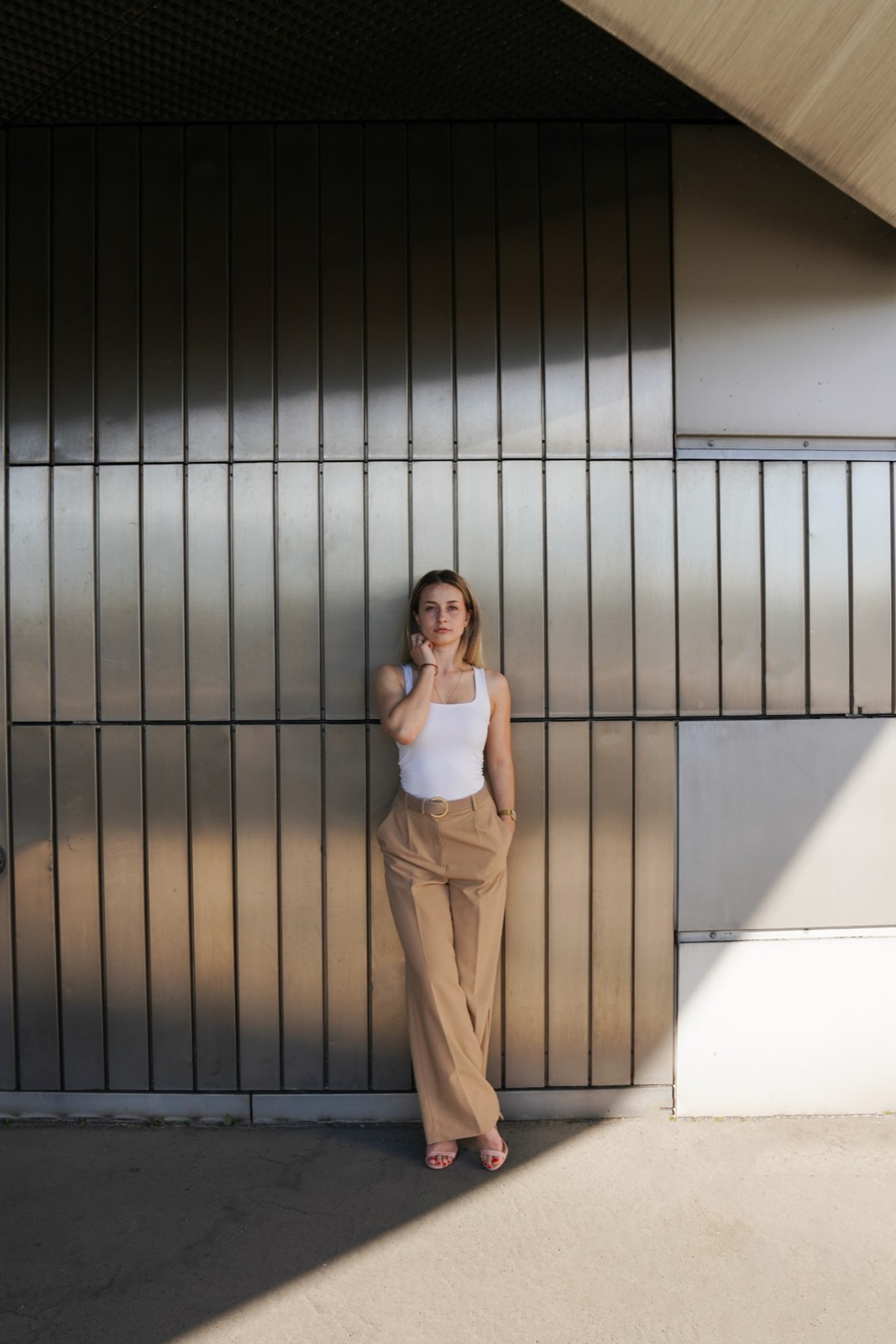 Tatjana Schäfer in weißem Top und beiger Hose vor einer Metallfassade