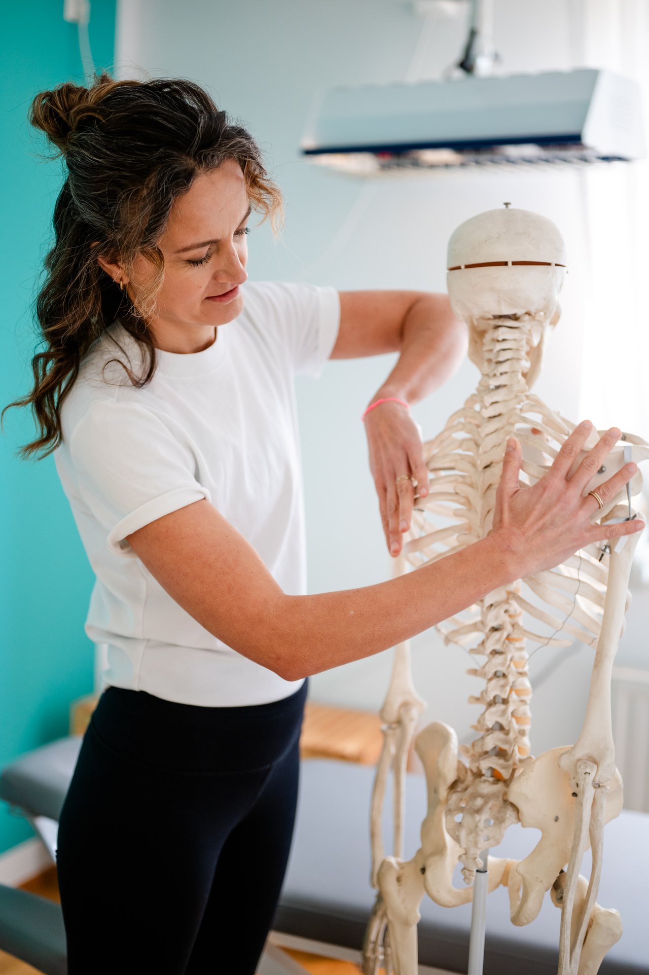 Physiotherapeutin erklärt die Wirbelsäule am Skelettmodell