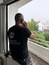 Mitarbeiter von Räum und Abrissprojekt im Firmenshirt telefoniert auf dem Balkon einer Baustelle