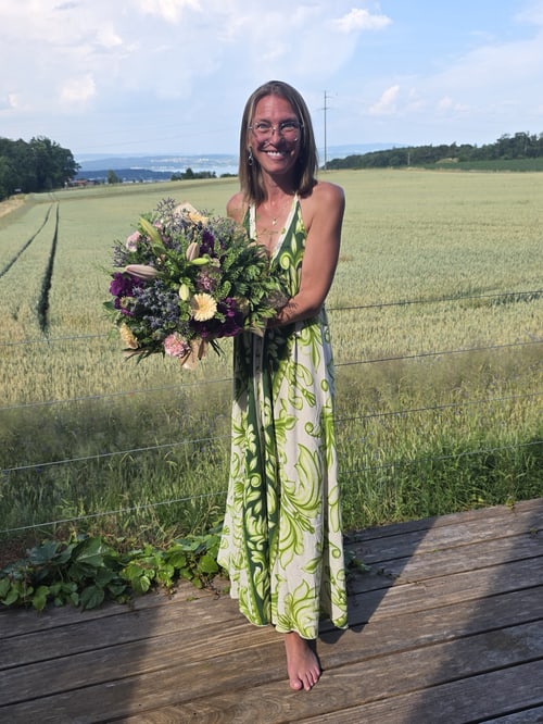 Gabriela Schaufelberger-Cadosch, klassische Homöopathin in Siegershausen, mit einem Blumenstrauss vor einem Kornfeld im Thurgau