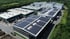 Luftaufnahme eines Industrieparks mit mehreren Hallen, viele Dächer sind mit Solarmodulen bedeckt.