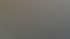 Ein Mann in einem roten Hemd sitzt lächelnd vor zwei Computermonitoren in einem Büro.