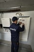 Techniker mit "enerly"-Logo auf dem Rücken, der an einem Sicherungskasten in der Nähe eines Wechselrichters arbeitet.