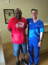 Two men smiling, one in a red shirt, one in blue scrubs.

