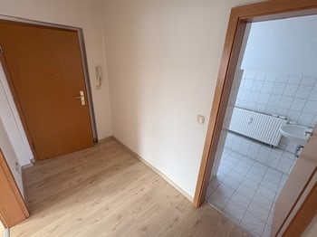 Leerer Flur mit Türen zu Nebenräumen und Blick auf ein gefliestes Bad