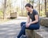 A woman in athletic wear sits on stone steps outdoors, holding her knee with a pained expression.