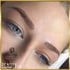 Nahaufnahme einer Frau mit blauen Augen und frisch microbladierten Augenbrauen, PhiBrows-Logo unten links.
