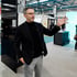 Ein Mann im Sakko präsentiert auf einer Messe neben einem Solarmodul und einer Wärmepumpe mit einer erklärenden Handbewegung.