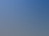 Strand mit Holzpfahlbuhnen, die ins Meer ragen, hellem Sand, blauem Himmel und strahlender Sonne.