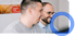 Zwei lächelnde Männer schauen auf einen Bildschirm, der rechte trägt eine Brille und ein blaues Hemd.