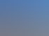 Anthrazitfarbenes Ziegeldach mit Dachfenster, einer Gaube aus Zinkblech und zwei Schornsteinen vor blauem Himmel.