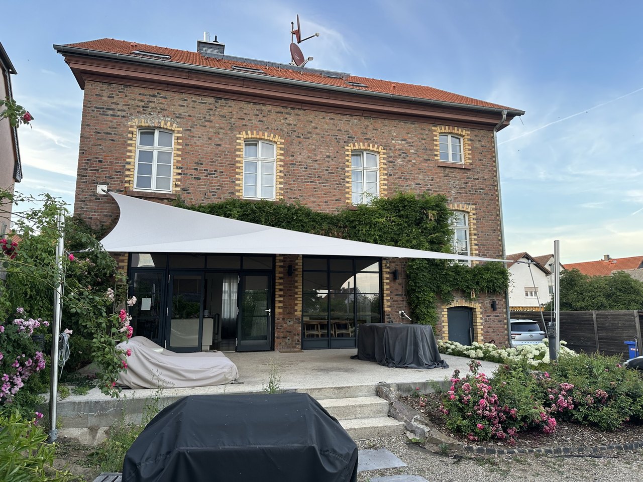 Backsteinhaus mit fest verspanntem Sonnensegel über der Terrasse