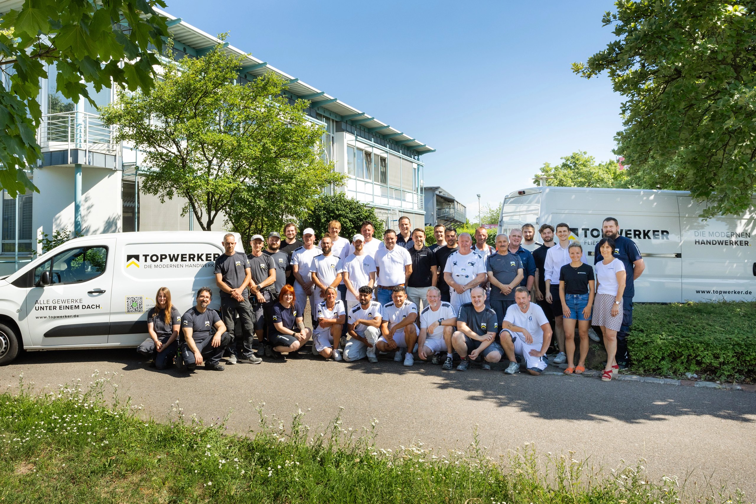 Das Team der Topwerker GmbH vor Firmenfahrzeugen