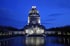 Völkerschlachtdenkmal in Leipzig nachts beleuchtet, mit Spiegelung im Wasserbecken.