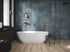 Badezimmer mit blau-grau marmorierter Wandfliese, freistehender weißer Badewanne und Holzboden in Eichenoptik
