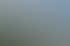 Mehrstöckiges Wohnhaus mit Balkonen vor einem bewaldeten Bergmassiv unter blauem Himmel.