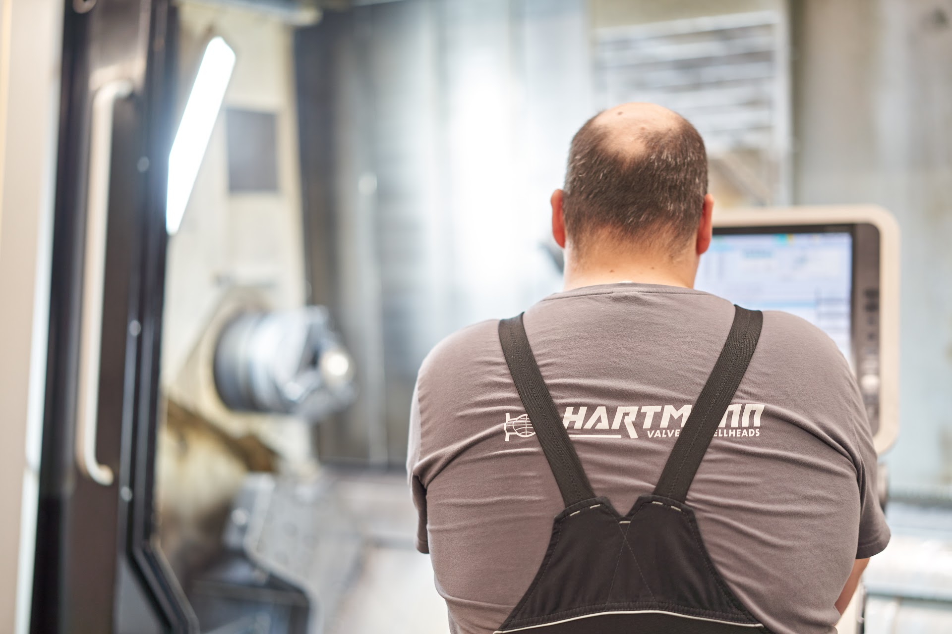 Mitarbeiter in Hartmann Arbeitskleidung an einer CNC Maschine in Celle
