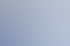 Lächelnde Frau mit kurzen Haaren und Brille sitzt am Schreibtisch im Büro vor einem Computer und weißen Aktenschränken.