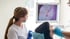 Zahnarzt und Assistentin untersuchen den Zahn eines Patienten auf einem Monitor.