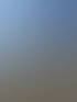 Ein gelbes Gebäude mit einem runden Eckturm mit Kuppel und Bäumen davor.