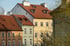 Mehrstöckige Stadthäuser in Pastellfarben mit roten Ziegeldächern und weißen Schornsteinen unter blauem Himmel.