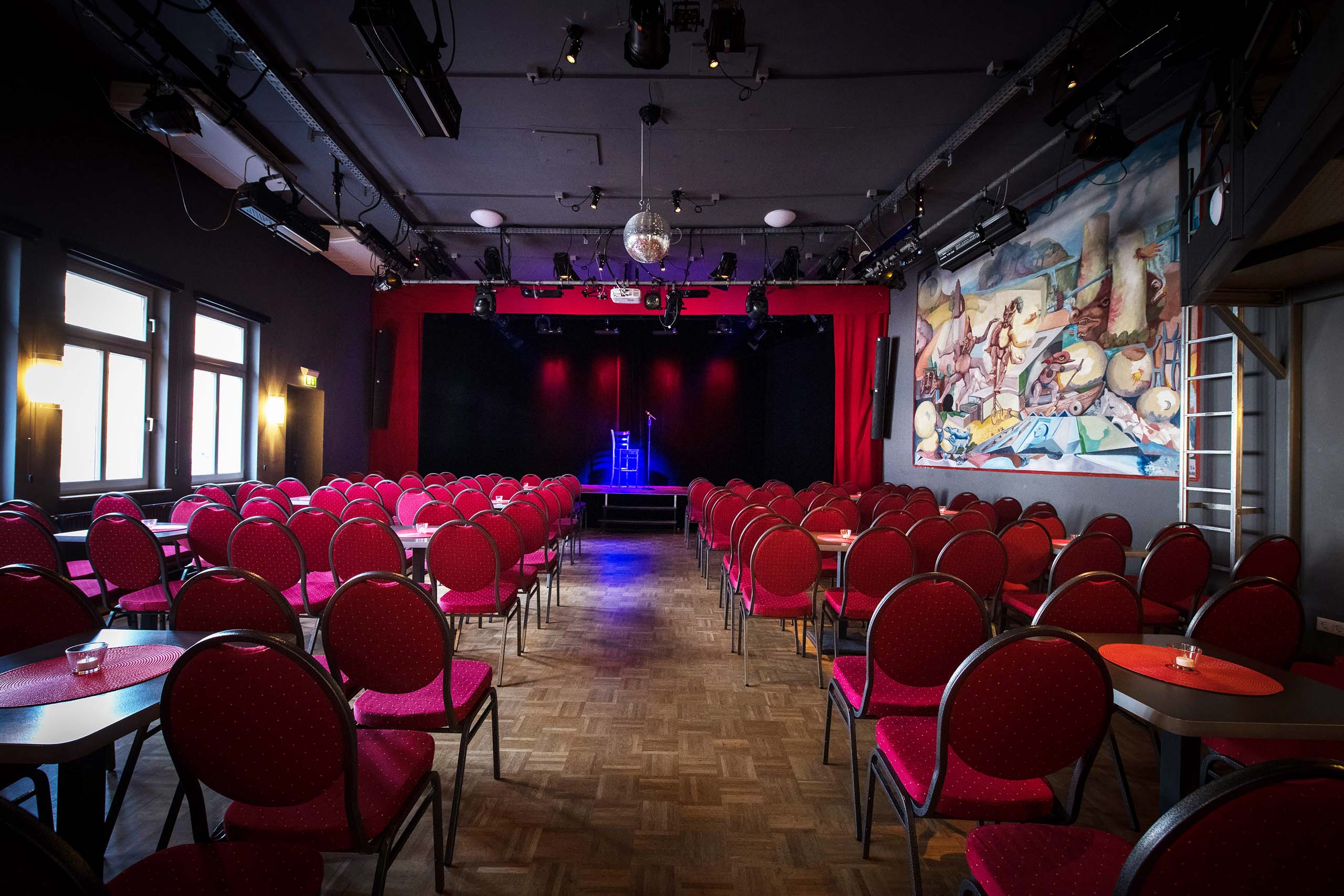 Zuschauerraum des Theaters im Pariser Hof mit roten Stühlen und Bühne