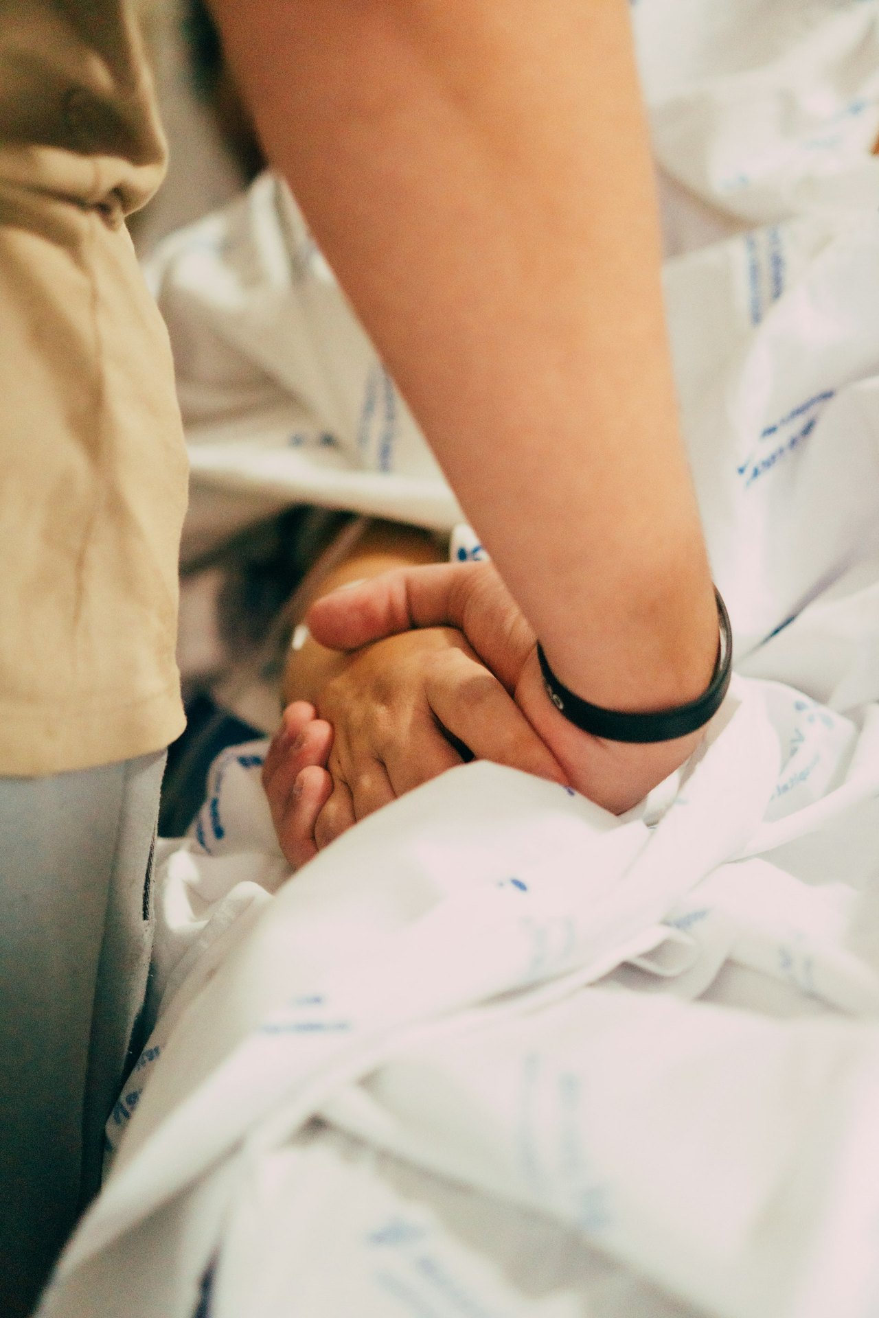 Pflegerin hält die Hand eines älteren Patienten