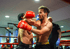 Zwei Kickboxer in roten und blauen Handschuhen kämpfen im Ring, ein Mann schlägt den anderen.