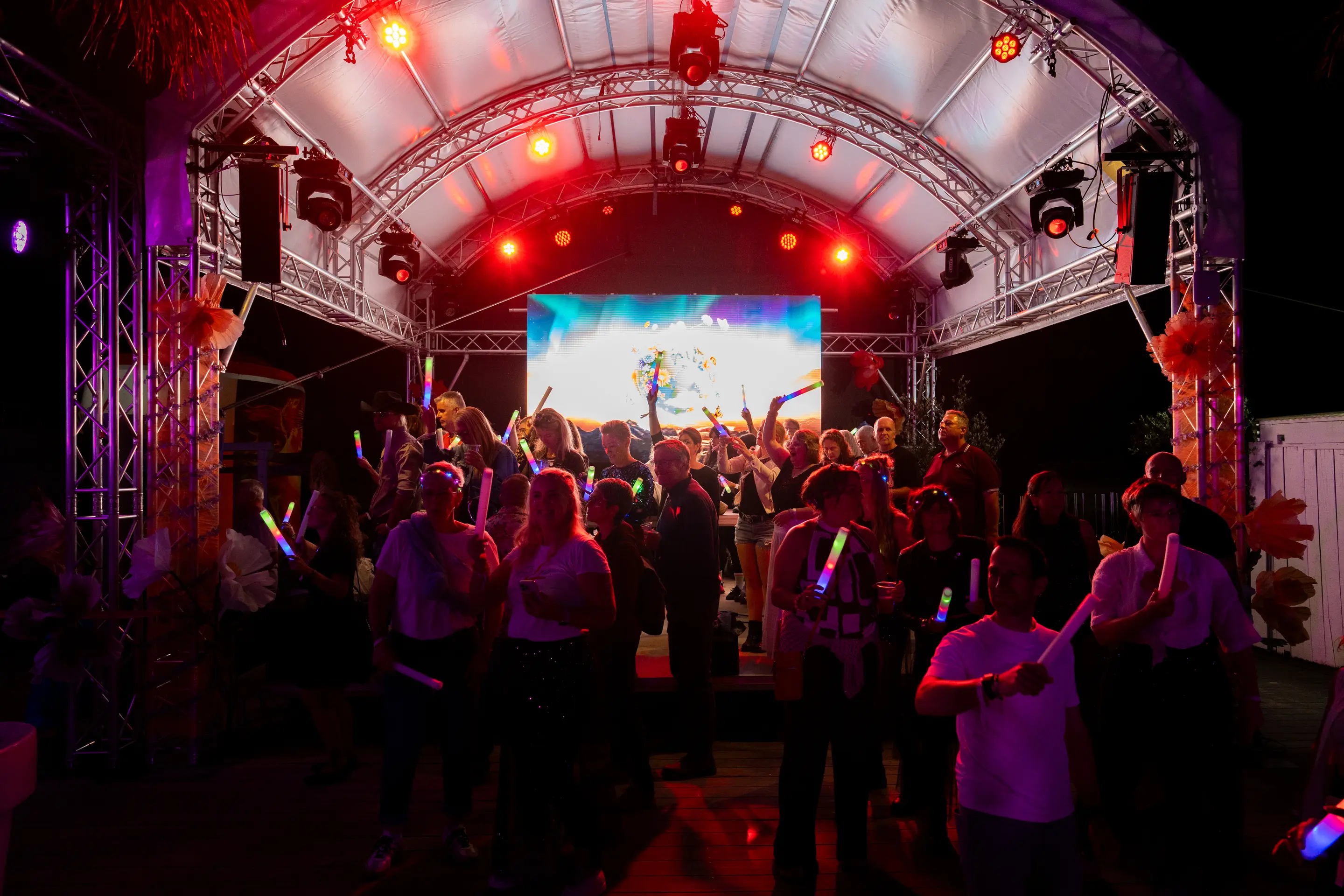 Bühne bei Nacht mit LED-Wand, Lichtshow und feierndem Publikum