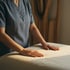 Hände ruhen auf einer mit Leinen bezogenen Massageliege