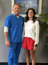 Chiropractic clinic staff smiling beside coastal artwork in treatment room