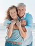 Happy senior couple enjoying wellness on a sunny beach.