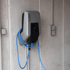 Graue MENNEKES-Ladestation für Elektroautos mit blauem Kabel an einer Wand.