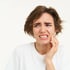 A young woman holding her cheek in pain, indicating jaw pain.