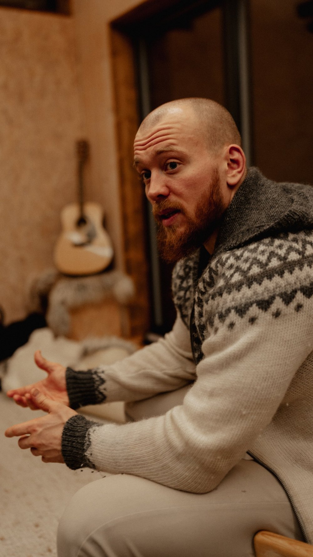 Mann erzählt vor einer Gitarre