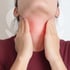Person holding their neck where the thyroid is located due to discomfort.