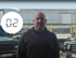 Ein Mann steht vor mehreren Land Rover Defendern; ein Kreis mit der Zahl "02" ist links.