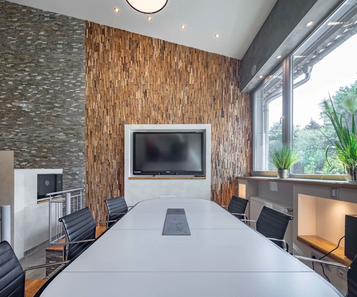 Besprechungsraum mit langem Tisch und Holzwand