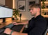 Ein Mann sitzt am Schreibtisch vor einem Monitor mit Tabellenkalkulation und bedient eine mechanische Tastatur.