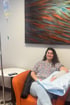 A woman smiles while sitting in an orange armchair receiving an IV infusion treatment in a medical clinic.