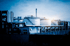 Große weiße Öltanks und Rohrleitungen einer Industrieanlage unter blauem Himmel.