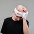 A man with a head injury holds his bandaged head.