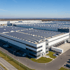 Großes Logistikzentrum mit Solarpanelen auf dem Dach und LKW-Docks an der Seite.